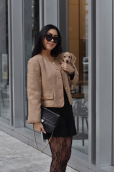 a lady in a black dress and a brown jacket